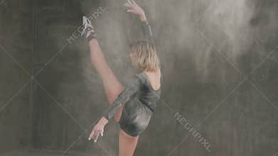 Female ballet dancer in black body suit perform on stage in theater and using white powder or white smoke dust. Dancer