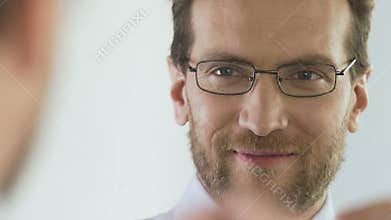 Attractive banker wearing eyeglasses and looking in the mirror, good mood