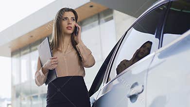 Beautiful lawyer walking to automobile, calling client, business communication