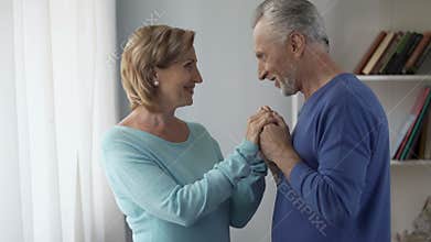 Aged man holding woman hands, kissing them in turns, lady being shy, coquette