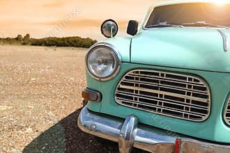 Headlight of a vintage classic car in the autumn golden sky at sunset time.