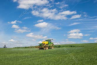 John Deere R4040i sprayer spraying in wheat field