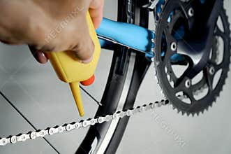 Mechanic oiling bicycle chain and gear with oil