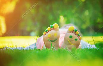 Child lying on green grass. Kid having fun outdoors in spring park.