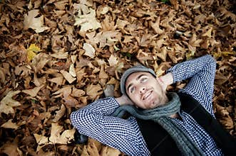 Man laying on autumn leaves.