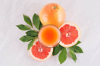 Summer bright fresh pink cocktail of grapefruits with green leaves, slice grapefruit on white wooden background, top view.