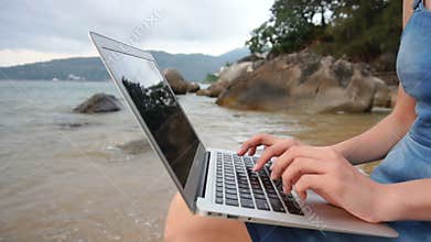 Slow motion author female writing novel on laptop at seaside.