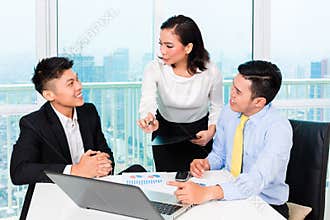 Asian banker counseling man in office