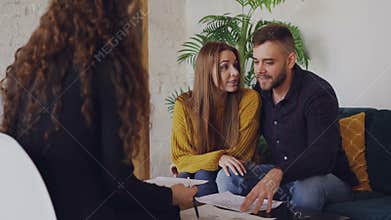 Loving boyfriend and girlfriend are looking at plan of house they are going to buy and talking to real estate broker