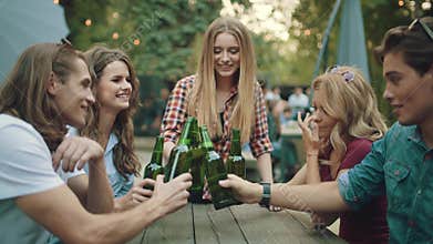 Friends drinking beer and toasting at outdoor party
