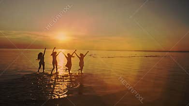 Group of Five Teenage Girls Run Into The Water, Celebrate On The Beach At Sunset. Beach party. Sun flare. Slow motion