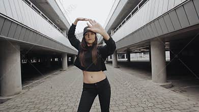Woman dancing modern vogue dance in parking lot, posing, contemporary freestyle in urban environment