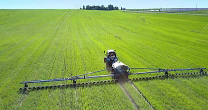 Backside tractor field sprayer drives on field to wood