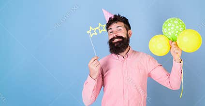 Hipster in star shaped glasses celebrates birthday. Party attributes concept. Guy in party hat with air balloons