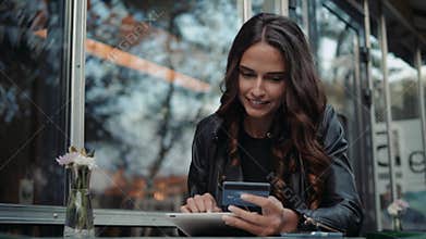 Young woman holding credit card and using laptop computer. Online shopping concept in modern cafe happy brunette girl