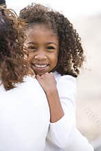 Close-up cute African-American girl in mom's arms