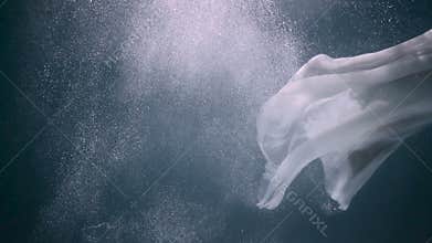 Beautiful woman swimming underwater in white elegant dress