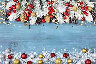 Christmas background with snowy fir tree and colorful holiday balls on blue wooden table top view. Greeting card with space
