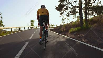 Cyclist riding a bike on an open road to the sunset