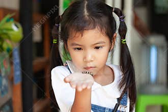 Cute asian child girl holding and playing with black caterpillar