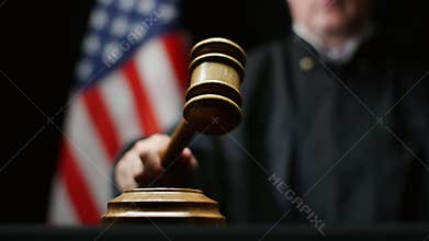 Judge hammering with wooden gavel against American flag in United States court room