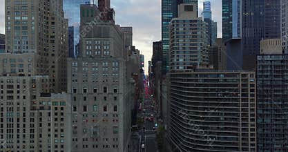 Forwards fly into space between tall buildings encircling Central park. Fly above wide avenue, red brake lights of cars