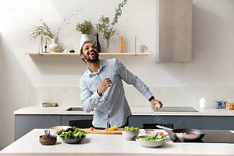 Happy cheerful millennial chef guy cooking, dancing to music