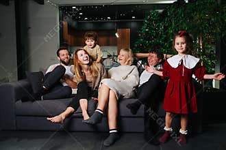 Happy big family sitting on a sofa in front of tv, celebrating christmas
