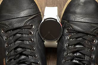 black sneakers and smart watches on the floor, fashion and new technologies, women&#x27;s fitness watch