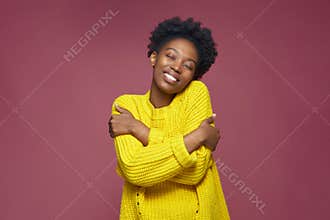 Love yourself, self acceptance. Smiling young african american woman embrace herself, closed eyes. Self-care concept
