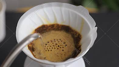 Barista pouring hot water from the kettle into the coffee filter