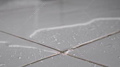 Water flows on floor covering white ceramic tile in bathroom