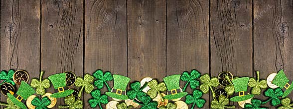 St Patricks Day bottom border with gold coins, shamrocks and leprechaun hats against a dark wood banner background