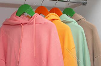 A set of unisex multi-colored hoodies in a closet on a hanger, unisex modern clothes.