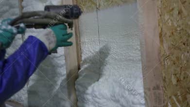 Builder apply insulating foam on the wall of a wooden house, foam insulation