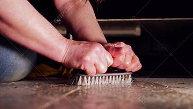 Woman scrubbing dirty floor with brush