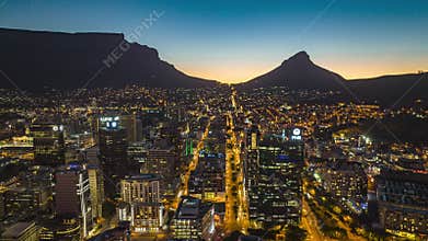 Evening aerial hyperlapse shot of downtown. Silhouette of mountain ridge in background. South Africa