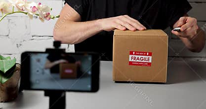 Man recording product unboxing video with mobile phone. social media marketing