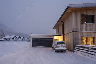Freshly snow cleared entrance in the dead of winter with a car in front of wooden house garage