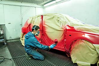 Worker painting a car.