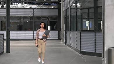 Front view of college female student walking in building campus corridor.