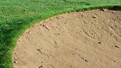Golf bunker showing sand and grass with copy space in grass