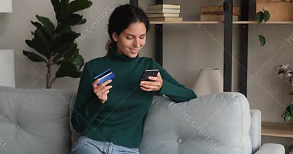 Woman holding smartphone and credit card makes secure payment