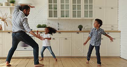 Funny active african dad dancing in the kitchen with kids