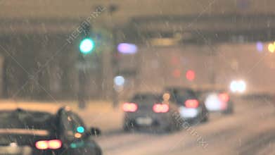 Defocused bokeh. Blurry cars driving on street during the night at snowy weather, focus on snow