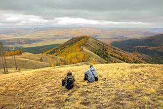 two mature tourists at the top of the ridge admire the Ural mountains and taiga