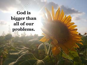 Faith inspirational quote - God is bigger than all of our problems.On nature background of the sun shine behind sunflower.