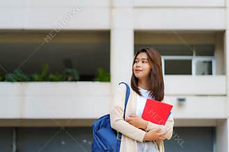 Portrait of a Asian college woman student carrying a backpack and standing in a school hallway at campus
