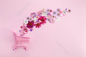 Flowers fly out of the pink shopping cart on a pink background. Season sale, spring shoping concept. Valentines day.