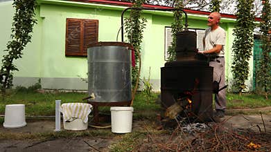 Man is manually mixing fruit marc in distillation apparatus for making domestic alcohol liquor